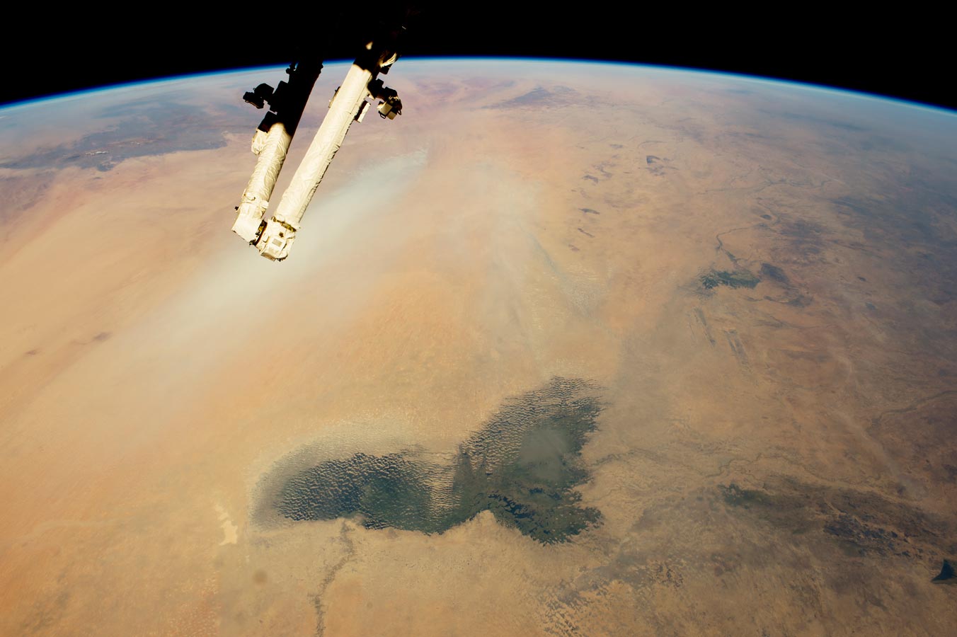 Озеро Чад и шлейфы пыли в пустыне Сахара в Африке. Темно-зеленые болота озера Чад выделяются на переднем плане. Даже если это более 200 километров в длину, современное озера Чад является лишь небольшим остатком огромного озера, которое занимало большую часть этого пейзажа в недавнем геологическом прошлом.