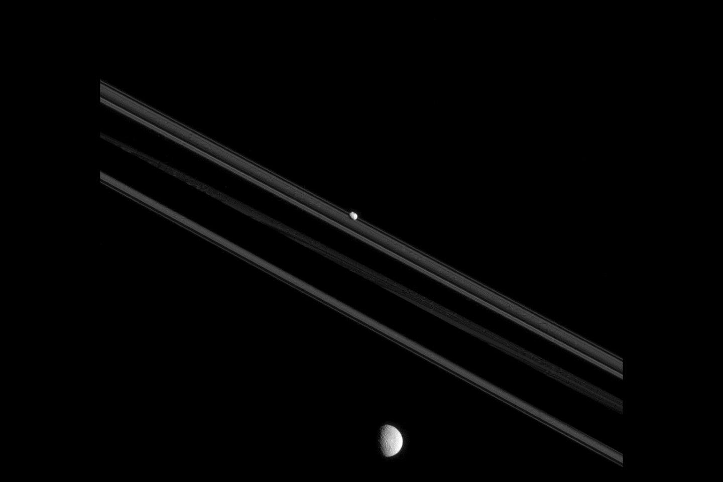 На  фото луны Мимас и Пандора на орбитах Сатурна. Пандора, «маленькае» по лунным стандартам (81 км в поперечнике), имеют удлиненную и нерегулярную форму. Мимас (396 километров в поперечнике), «средняя» луна, преобразованная в сферу из-за самогравитации при ее  более высокой массе.