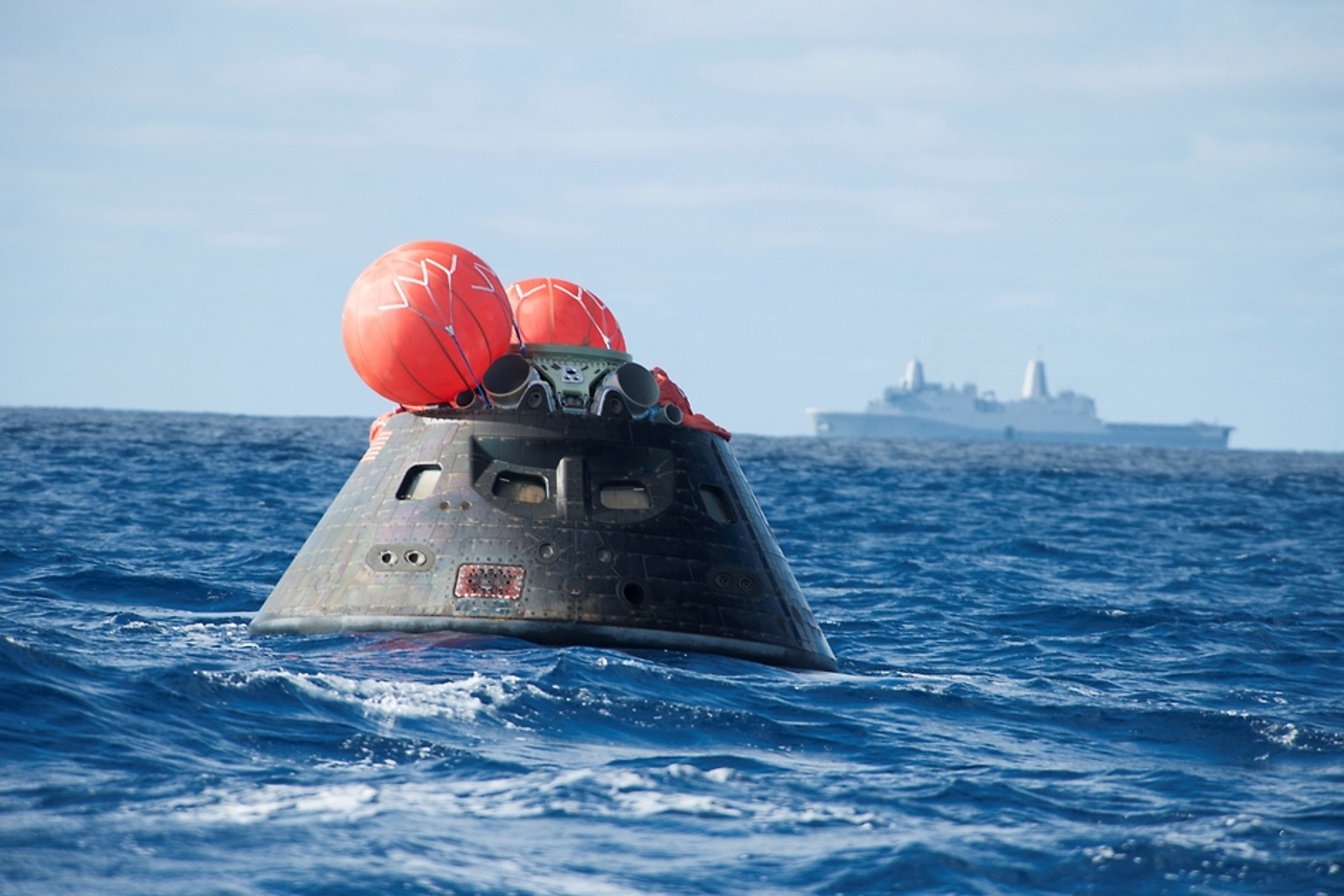 5 декабря 2014 года космический аппарат «Орион» был запущен в космос и через несколько часов капсула была сброшена в Тихом океане. Военно-морской корабль на заднем плане поднял капсулу после ее безопасной посадки.