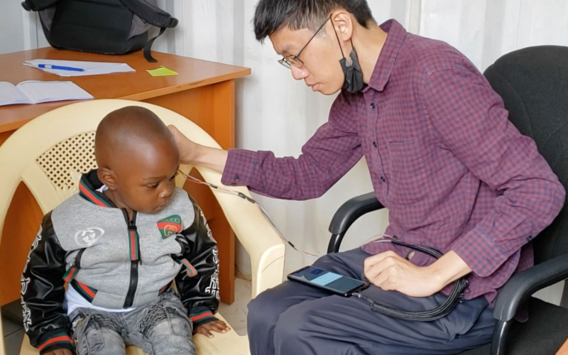 Ведущий исследователь Джастин Чан использует установку для проверки слуха ребенка.